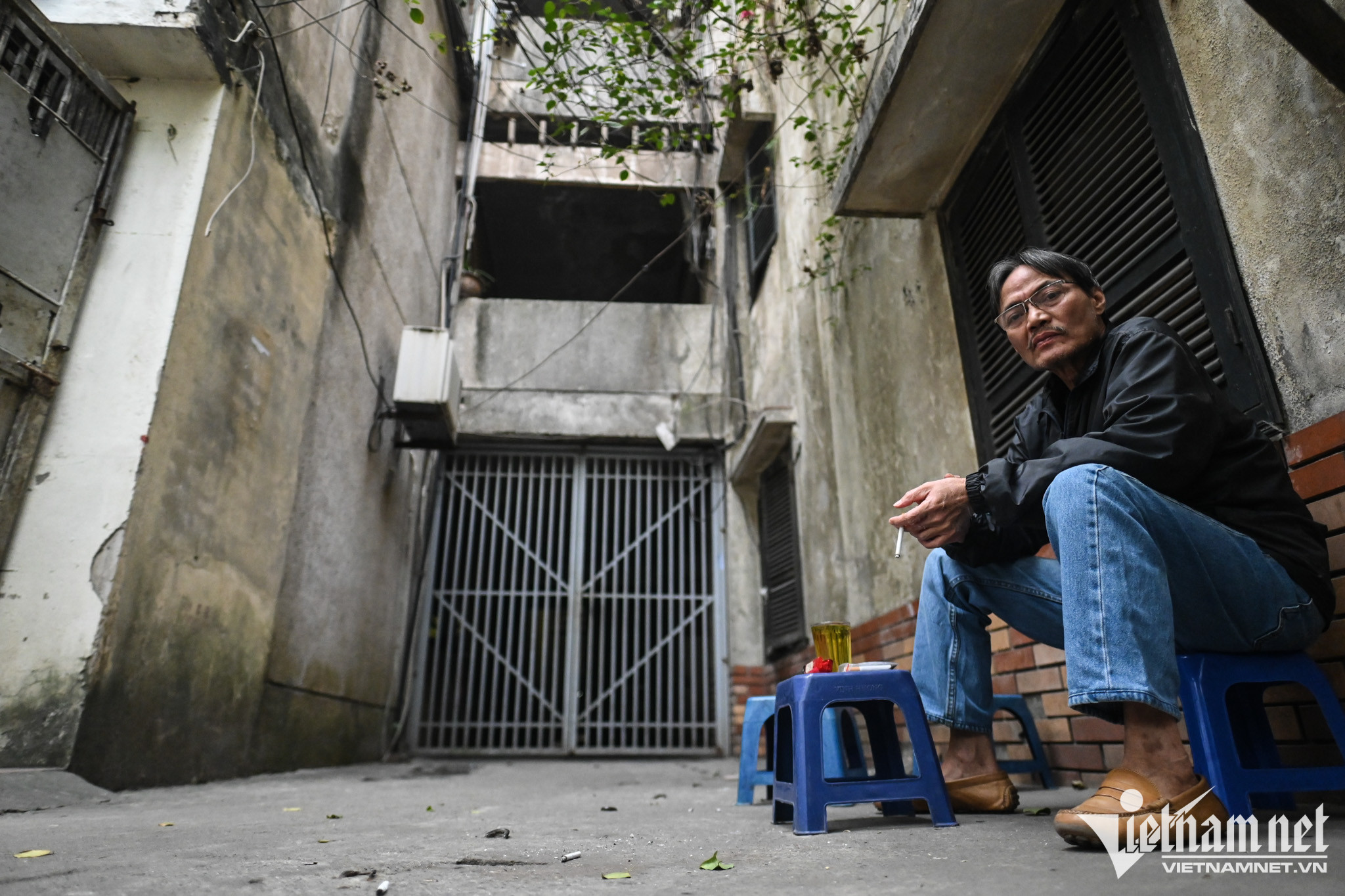 Lối cổng chính đi vào khu tập thể luôn trong tình trạng đóng cửa. Phía dưới, một vài hộ dân vẫn kinh doanh quán trà đá.