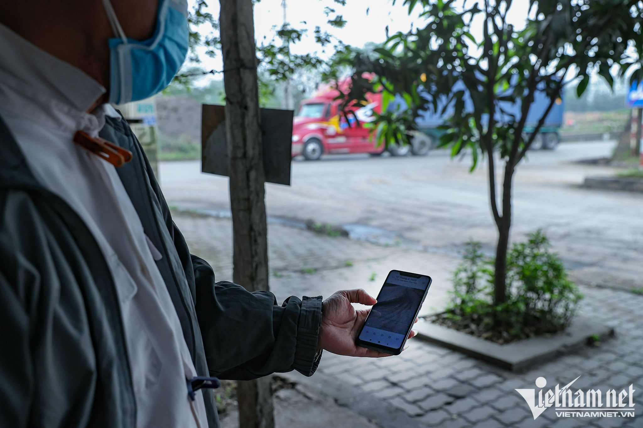 Ông Long mở điện thoại cho phóng viên xem hình ảnh anh chụp những hôm bụi dày trên đường. Ảnh: Lê Anh Dũng 
