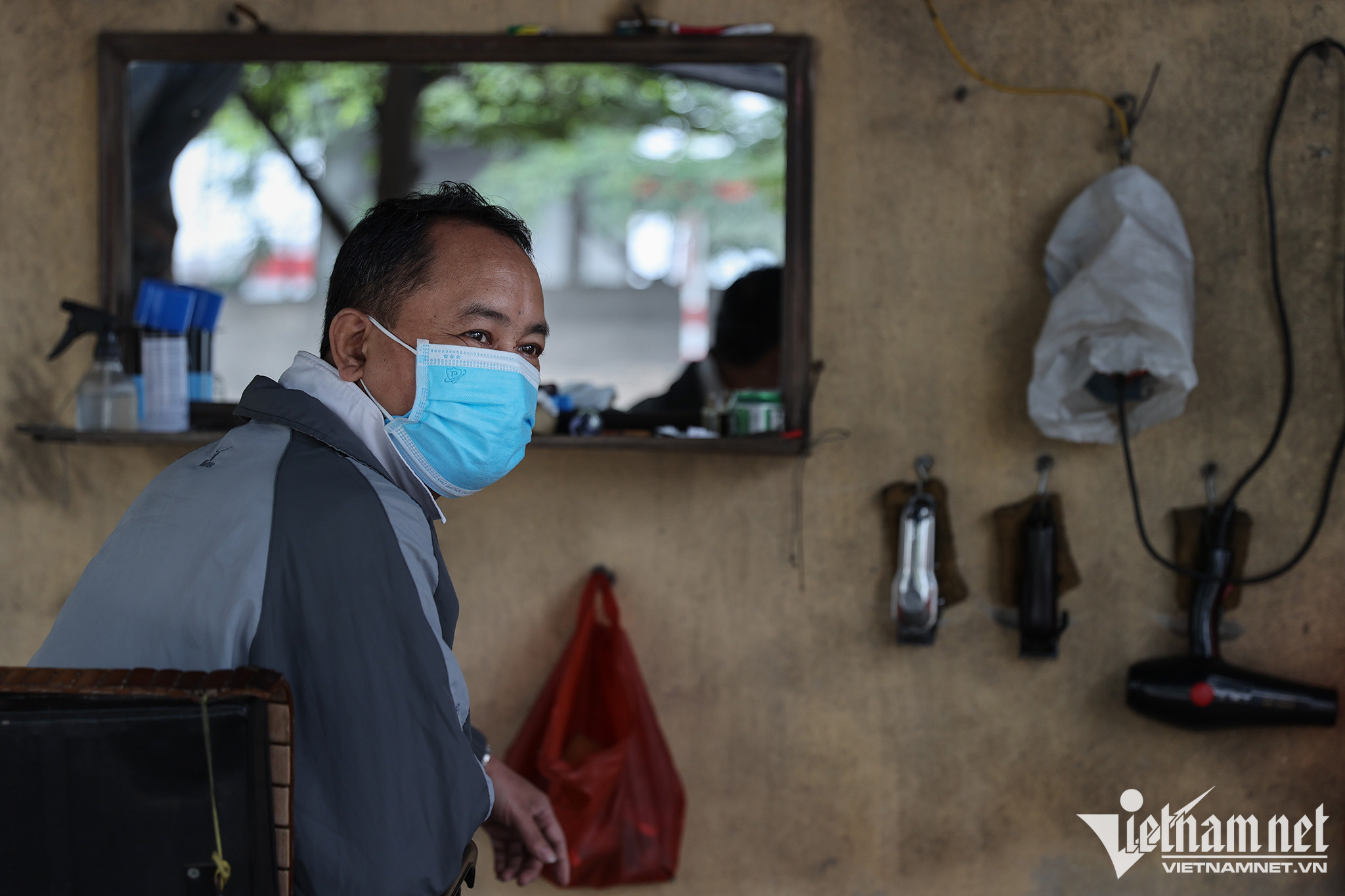 Hành nghề cắt tóc trên con đường chạy ngay ngoài cảng Việt Trì hơn chục năm nay, ông Lương Vĩnh Long luôn phải đeo 2 chiếc khẩu trang với mong muốn hạn chế tối đa lượng bụi hít vào phổi. Ảnh: Lê Anh Dũng