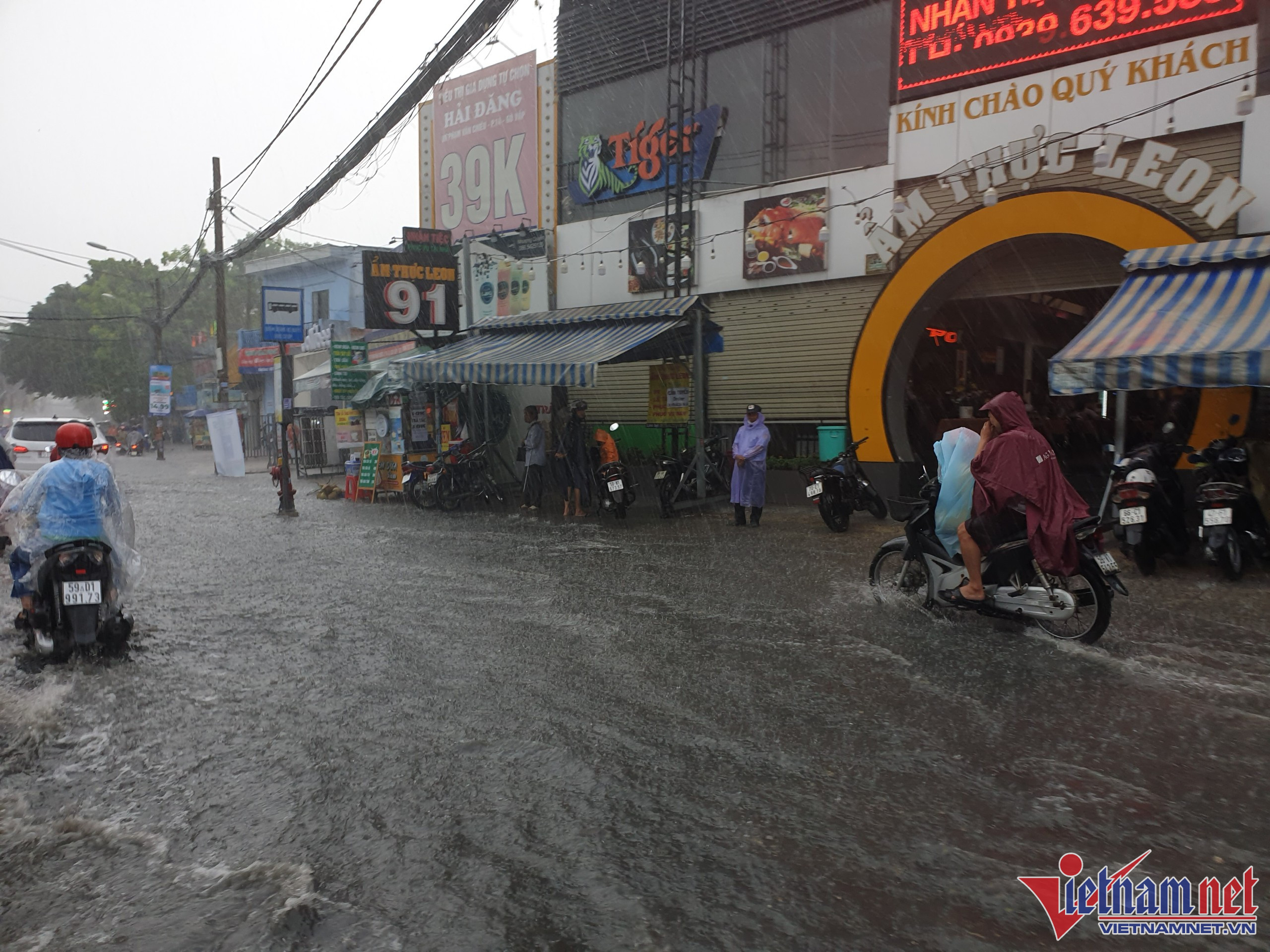 Đường Phạm Văn Chiêu (quận Gò Vấp) ngập lênh láng, nhiều người đi đường phải tấp xe lên lề đường để trú mưa.