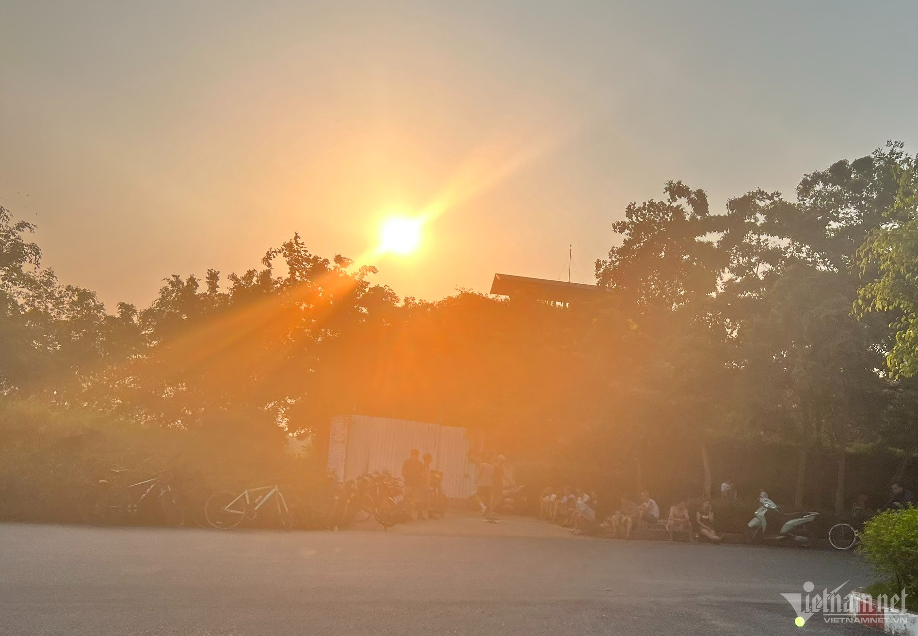 Người dân ngồi dưới tán cây tránh nắng nóng trên đường vào khu du lịch sinh thái Tuần Châu (Quốc Oai).