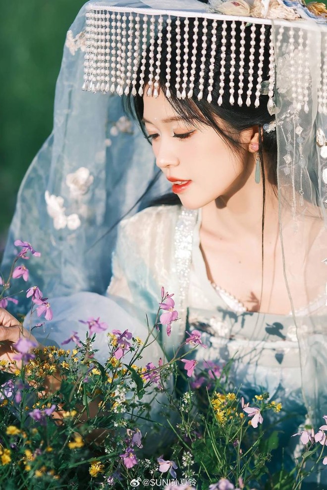 Suni Hạ Linh khoe trọn vẻ đẹp trong trẻo, thanh thuần cùng làn da trắng phát sáng trong tạo hình cổ trang. Kiểu tóc uốn lượn buông xõa kết hợp cùng trâm cài tóc khiến nữ ca sĩ Việt Nam như hóa một tiểu thư đài các với vẻ ngoài thanh tao, nhã nhặn. Ngoài ra, makeup look nhẹ nhàng, trong veo nhấn vào màu son bóng càng giúp tôn lên đường nét gương mặt thanh tú của Suni Hạ Linh