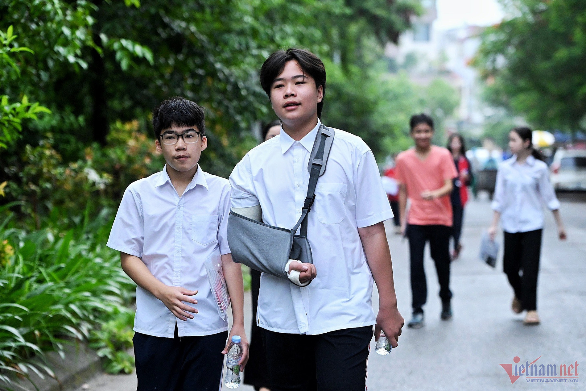 6h30, Phạm Lưu Quang Huy có mặt tại điểm thi. Em là thí sinh đặc biệt nhất tại điểm thi này bởi bị gãy tay phải. Đi cùng Huy trong ngày thi chính thức là Phú An (học sinh lớp 8) với nhiệm vụ hỗ trợ Huy viết trong quá trình làm bài. “Dù ngồi 1 mình 1 phòng thi nhưng em vẫn cảm thấy rất tự tin vì mình đã ôn tập tốt”, Huy nói. Ảnh: Thạch Thảo