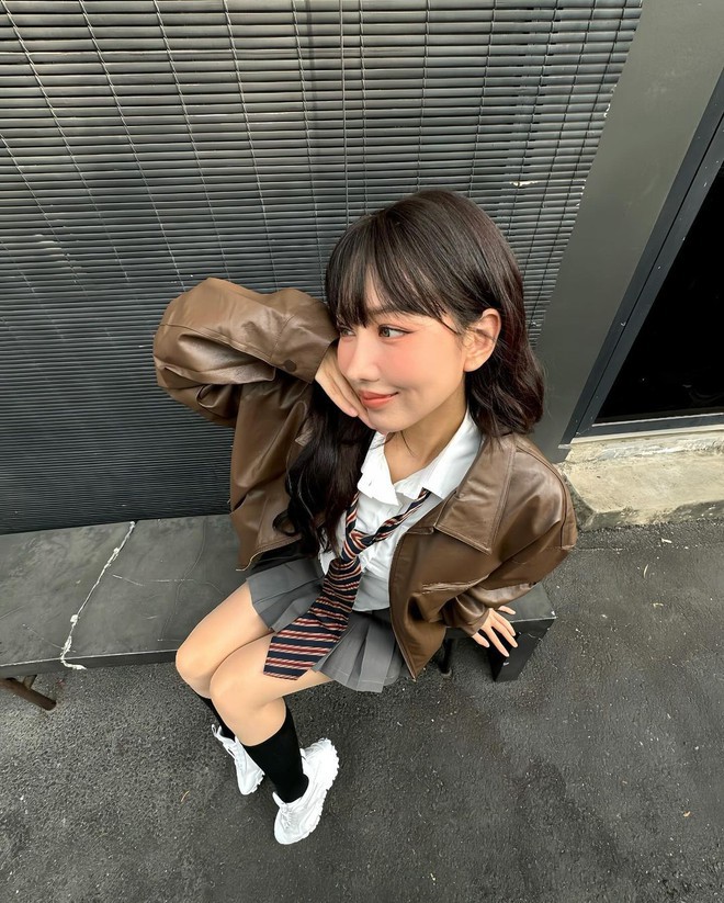 Quay lại hình tượng trẻ trung, tinh nghịch, cô nàng lựa ngay 1 set nữ sinh siêu hack tuổi. Mini skirt xám hot hit được nữ ca sữ phối cùng sơ mi thắt cà vạt màu sắc làm nét nhấn nhá thú vị. Hoàn chỉnh outfit bằng em áo khoác da nâu bóng trendy.