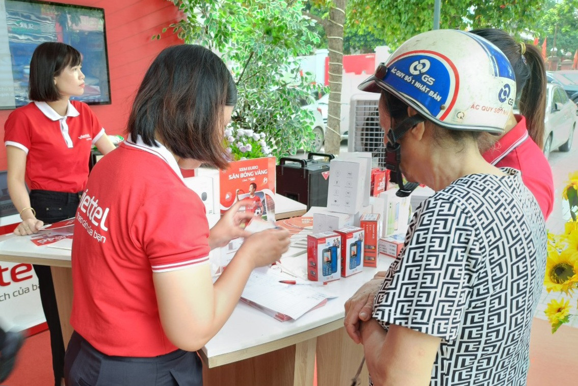Nhân viên nhà mạng hướng dẫn, tư vấn người dân đổi điện thoại cục gạch 2G lên 4G. Ảnh: Viettel