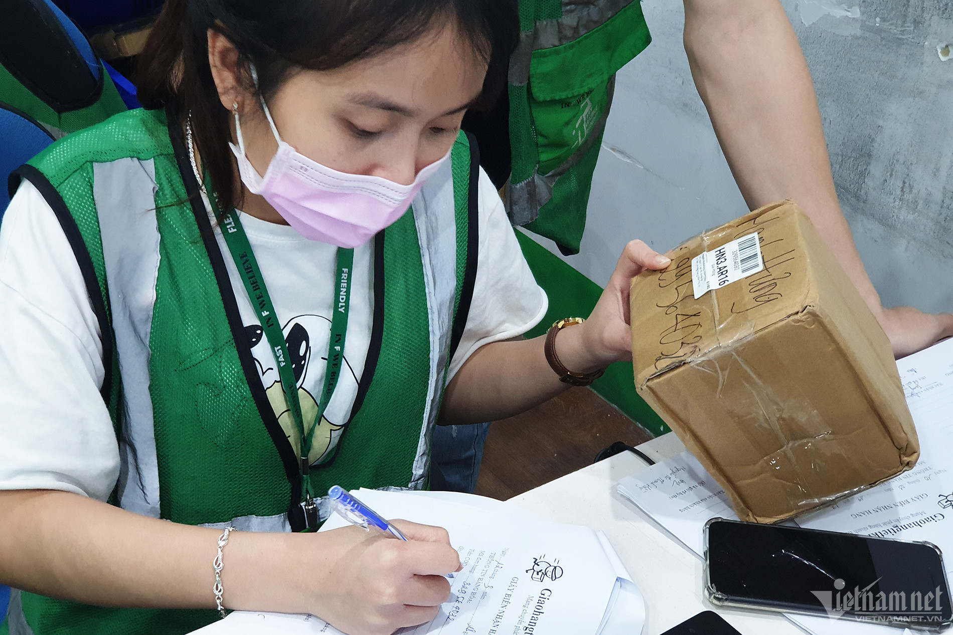 Một nữ nhân viên chuyển phát đang phân loại đơn hàng. Ảnh: Trọng Đạt