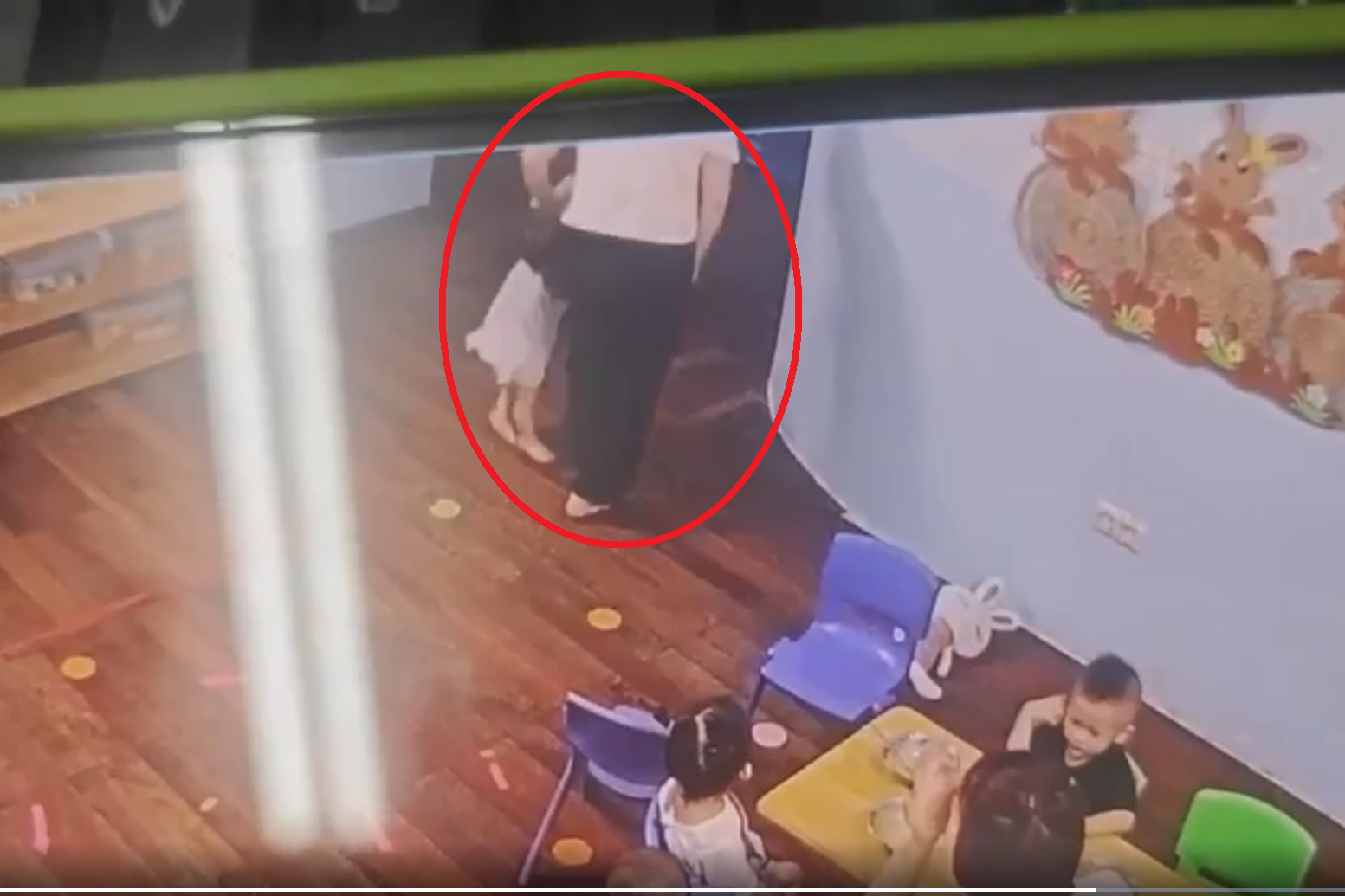 Hình ảnh cô giáo xách một tay bé 13 tháng tuổi. Ảnh cắt từ clip.