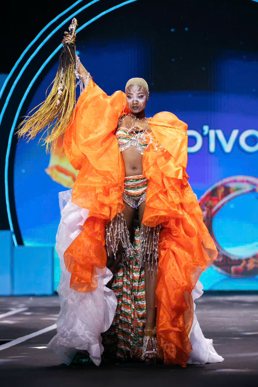 Hoa hậu Côte d’Ivoire gây chú ý với phần tà trang phục mô phỏng màu cờ quốc gia cùng màn lột tóc giả ấn tượng. 