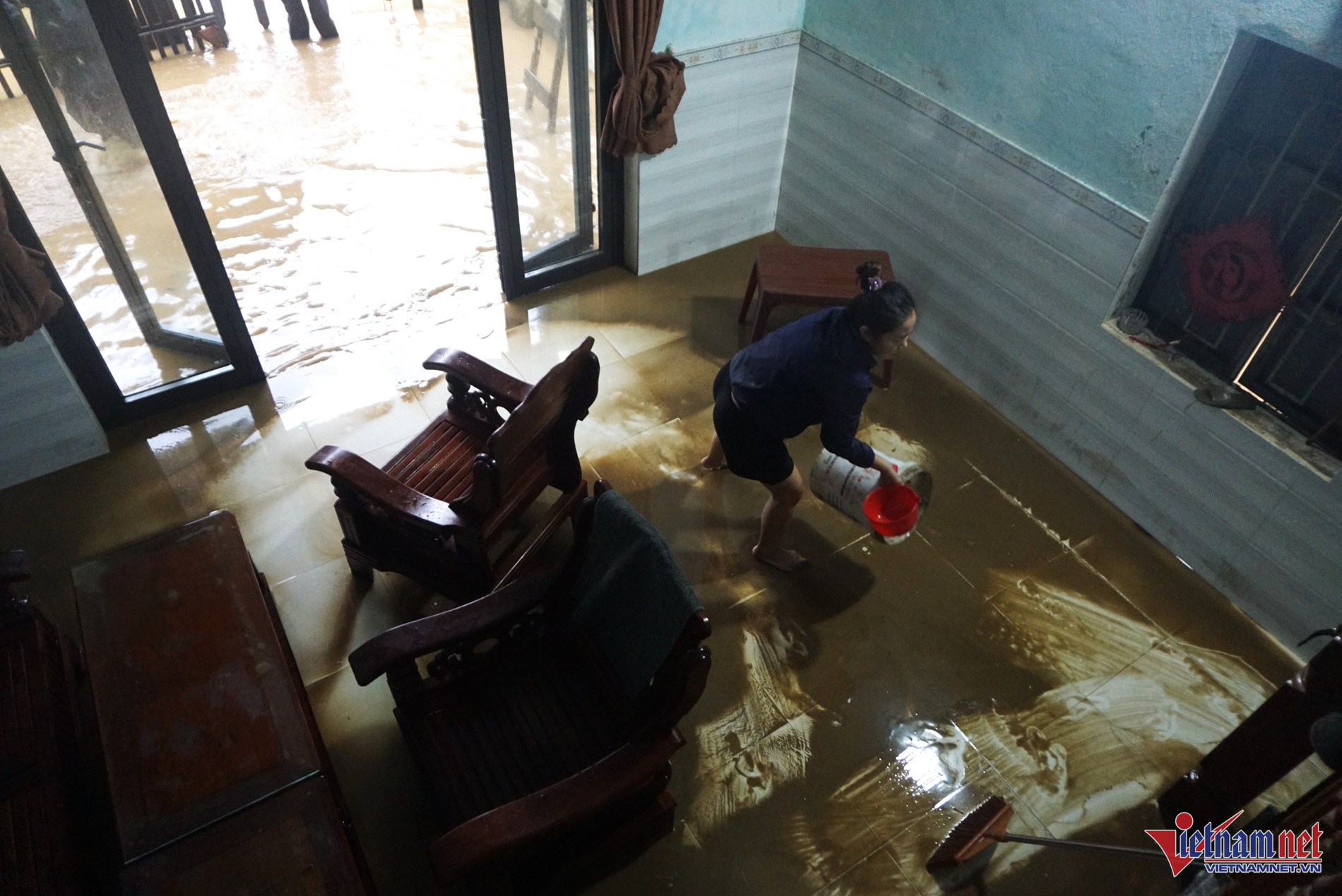 Chị Nguyễn Thị Thu Hà tận dụng nước ngập phía trước nhà để dọn, rửa bùn non