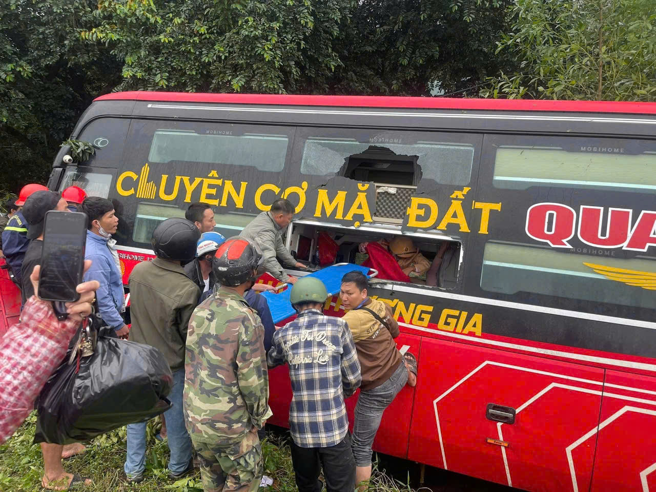 Lực lượng chức năng cùng người dân hỗ trợ đưa hành khách mắc kẹt bên trong xe ra ngoài. Ảnh: CTV