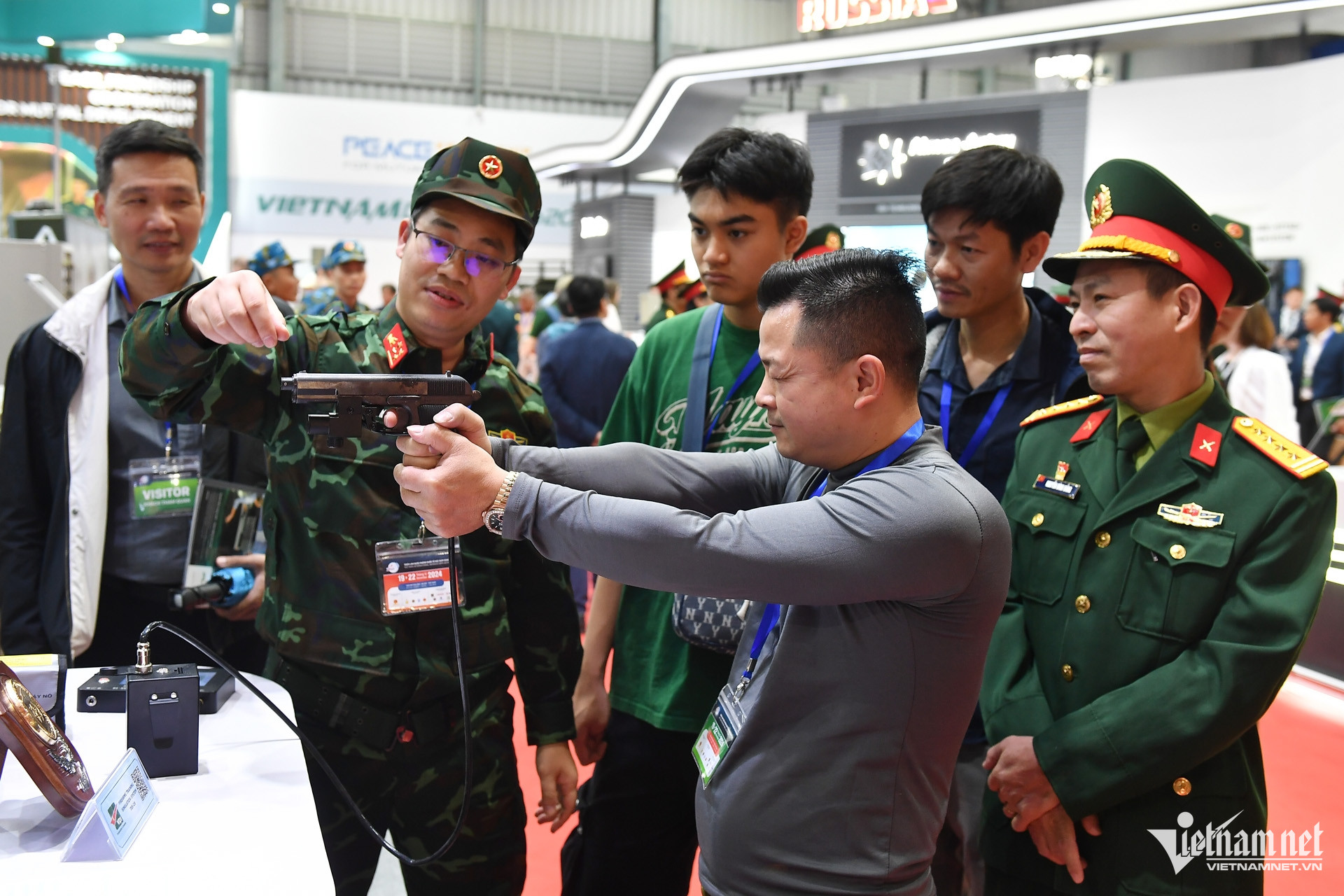 Tại một gian hàng khác, nhiều khách lần lượt thử dùng súng ngắm bắn tính điểm điện tử theo sự hướng dẫn của kỹ thuật viên.