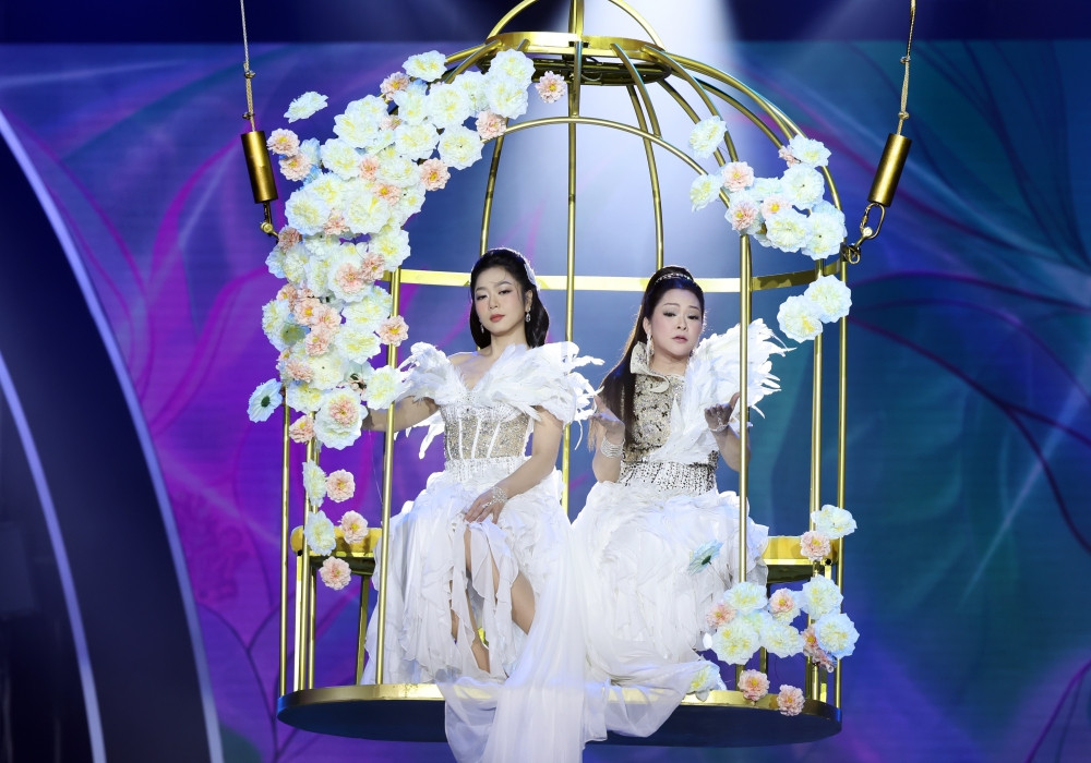 Như Quỳnh mở màn ấn tượng cùng Hà Thanh Xuân với mô hình chiếc lồng chim thả từ trên cao. Cả hai diện váy trắng đính lông vũ, hòa giọng trong liên khúc “Yêu nhau đi - Yêu nhau bốn mùa”.