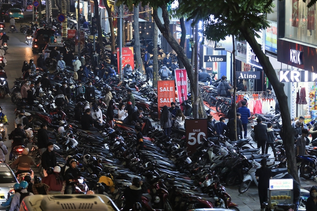 Lúc 22h00, nhiều cửa hàng thời trang trên đường Nguyễn Trãi đông nghịt người đến mua sắm, xe máy được xếp tràn lan dưới lòng đường