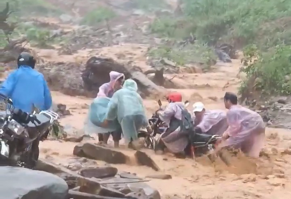 Thót tim cảnh mẹ cõng con vượt lũ trên cây cầu tạm, đoàn người vật lộn qua dòng nước cuồn cuộn Thót tim cảnh mẹ cõng con vượt lũ trên cây cầu tạm, đoàn người vật lộn qua dòng nước cuồn cuộn