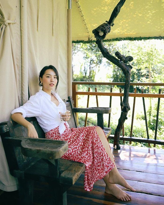 Hà Trúc biến áo sơ mi thành áo khoác ngoài và buộc phần tà áo lại để mix cùng chân váy hoa xẻ tà đúng chất mùa hè mát rượi.