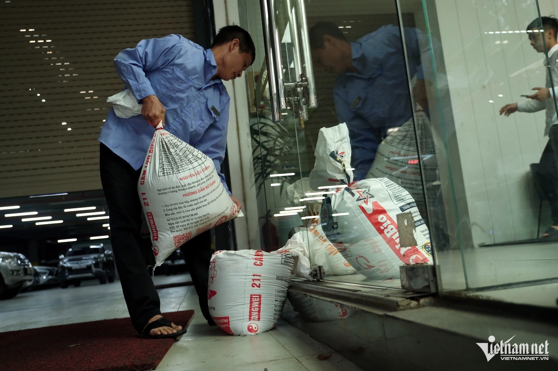 Một số bao cát đã được dựng lên chắn trước cửa. Một chủ gara cho biết việc lựa chọn bao cát để chắn là bởi khi ngấm nước, cát trong bao sẽ trở nên nặng hơn và có độ chắc chắn. Ảnh: Hùng Nguyễn