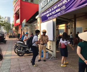 Hai chiến sỹ CSGT đứng trước cổng trường phát nước miễn phí cho thí sinh và phụ huynh ở Sài Gòn