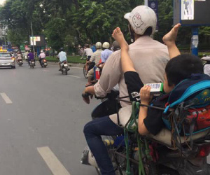 Bức ảnh cậu bé ngồi vắt vẻo ở yên sau, gác 2 chân lên vai mặc cho bố đang chạy xe gây tranh cãi