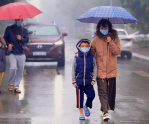 Ảnh: Cha mẹ học sinh trường Tiểu học Xuân Phương đội mưa đưa con đi xét nghiệm COVID-19