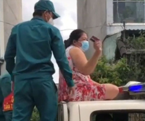 Không đeo khẩu trang, người phụ nữ còn trèo lên nóc xe cảnh sát ngồi, múa may làm loạn nơi công cộng