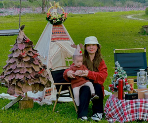 Mẹ trẻ nhặt lá bàng khô ở công viên làm cây thông Noel