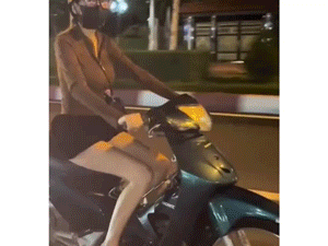 Cô gái vắt chéo chân, buông 2 tay tạo hình trái tim khi lái xe trên phố