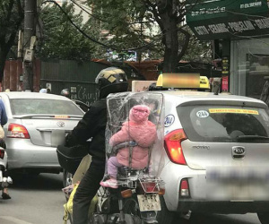 Giữa một sớm mai rét mướt, bức ảnh bé con ngồi sau xe bố trùm kín nilon khiếm lòng ta ấm áp
