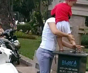 Mẹ bế con trai rửa chân nơi ven đường, cư dân mạng phẫn nộ vì chi tiết này