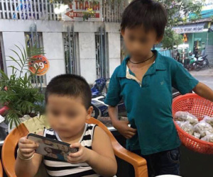 1 bức ảnh, 2 số phận: Hình ảnh cậu bé bán hàng rong lặng lẽ 'xem ké' điện thoại của người bạn cùng tuổi bên bàn lẩu khiến nhiều người xót xa