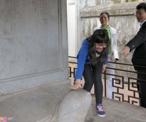 Mẹ chỉ đạo con trèo rào sờ đầu rùa cầu may ngày Tết