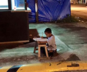 Cậu bé vô gia cư dùng ánh đèn lọt ra từ cửa hàng McDonald's để học bài