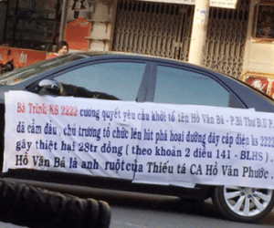 Tạm giữ người phụ nữ lái ô tô căng băng rôn bêu tên cán bộ diễu phố