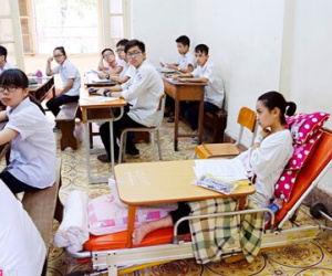 Ngồi trên giường chuyên dụng bệnh viện làm bài thi lớp 10