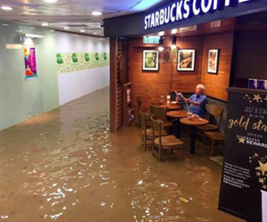 Cụ ông bình thản đọc báo trong quán cafe ngập lụt ở Hong Kong