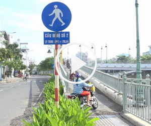 Xe máy luồn lách qua khe hẹp trên cầu đi bộ ở Sài Gòn