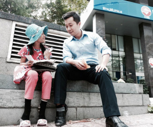 Anh nhân viên ngân hàng dành giờ nghỉ trưa mỗi ngày để dạy chữ cho cô bé vé số ngay trên vỉa hè Sài Gòn