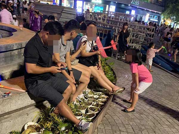 Bức xúc hình ảnh hàng chục người ngồi bên đài phun nước phố đi bộ Hồ Gươm, thản nhiên đạp chân thẳng lên hàng hoa trang trí