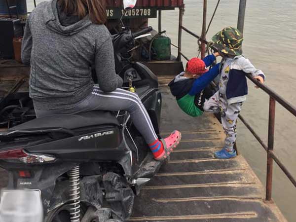Phẫn nộ trước hình ảnh người mẹ mải xem điện thoại để 2 con nhỏ vắt vẻo đu trên lan can đò đầy nguy hiểm