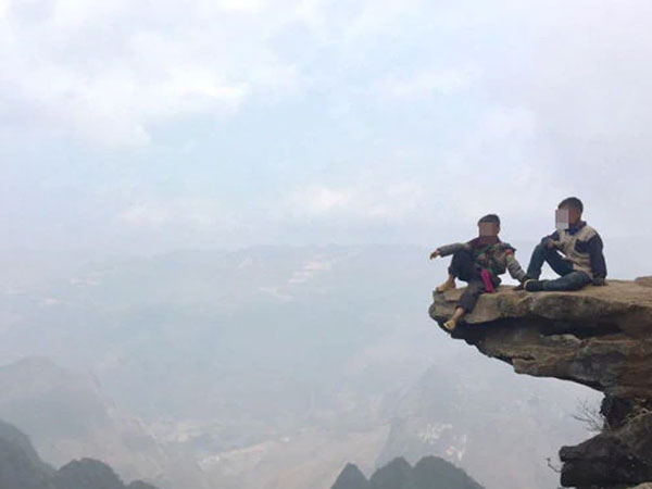 Hai bé trai ngồi trên mỏm đá cao treo leo ở Hà Giang để 'thu tiền' check-in khách du lịch