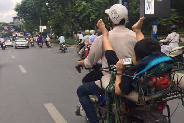 Bức ảnh cậu bé ngồi vắt vẻo ở yên sau, gác 2 chân lên vai mặc cho bố đang chạy xe gây tranh cãi