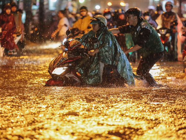 Người Sài Gòn vật lộn với đường ngập lút bánh xe, nước chảy cuồn cuộn như thác trong đêm mưa lớn