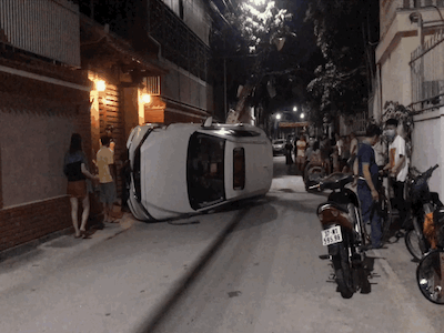 Xế hộp đâm gãy cột điện rồi lật nghiêng giữa đường, người trong xe bò ra từ cửa sổ trời