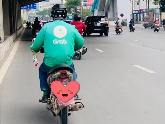 Khoảnh khắc ấm áp ngày 8/3: Người đàn ông đi xe ôm công nghệ tay cầm theo bông hồng nhỏ xinh để dành tặng người phụ nữ mình yêu thương