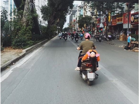 Hình ảnh bé gái ngủ gục, nằm hẳn ra yên xe máy trên phố Hà Nội khiến ai cũng phải thót tim