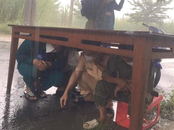 CSGT và đội trực chốt kiểm dịch nép dưới gầm bàn trú mưa, nhìn xuống đôi dép lại càng thêm xót xa