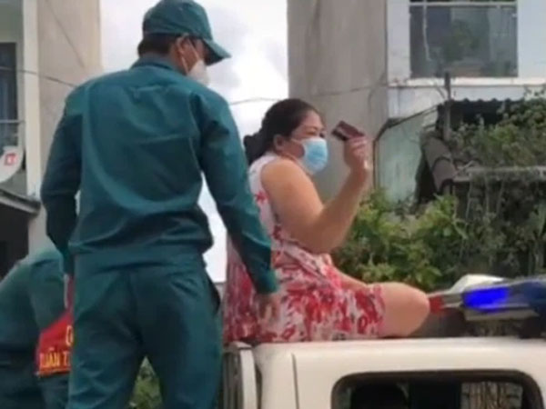 Không đeo khẩu trang, người phụ nữ còn trèo lên nóc xe cảnh sát ngồi, múa may làm loạn nơi công cộng