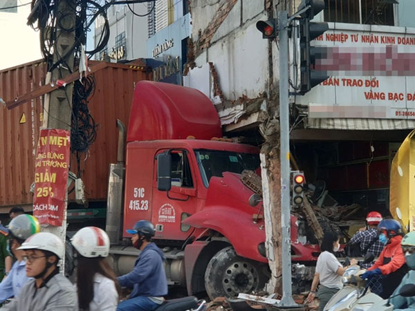 Húc văng nhiều mét dải phân cách, xe container tông sập tiệm vàng