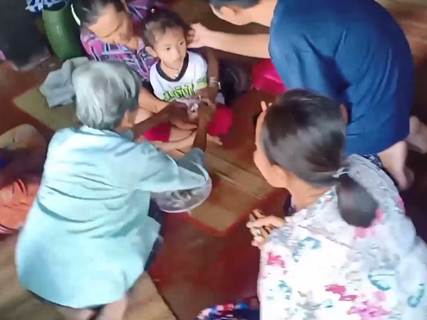 Người dân buộc chỉ vào cổ tay cho bé gái sống sót duy nhất sau vụ thảm sát tại trường mầm non Thái Lan để cầu may mắn
