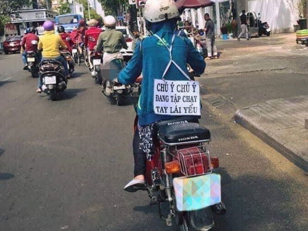 Người phụ nữ đeo tấm bảng sau lưng khi chạy xe máy, vừa nhìn ai nấy cũng chủ động giữ khoảng cách