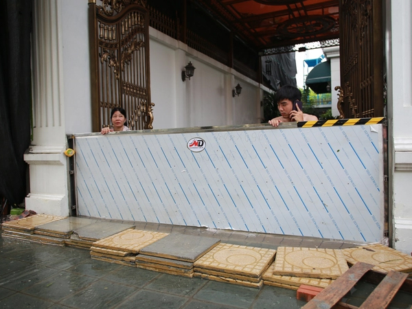 Trời hửng nắng, nhiều tuyến đường ở Hà Nội vẫn ngập sâu, người dân dùng tấm chắn để ngăn nước tràn vào nhà